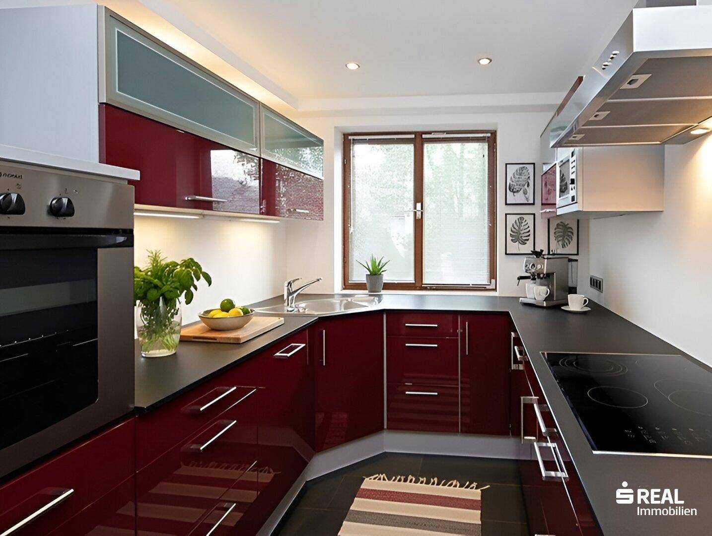 Moderne Küche mit glänzenden roten Fronten, Induktionskochfeld und Fenster.