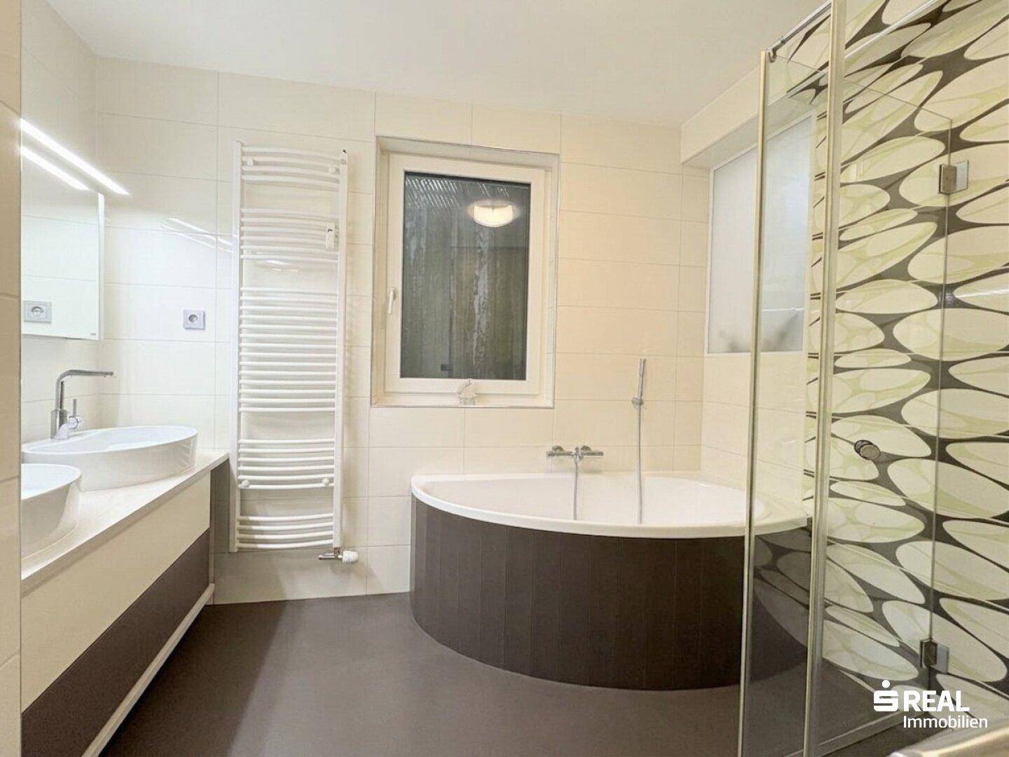 Modernes Badezimmer mit runder Badewanne, separater Dusche und Doppelwaschbecken.