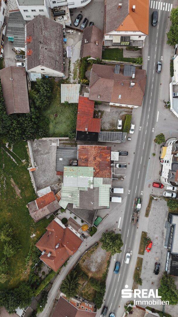 Vertikale Luftaufnahme einer städtischen Bebauung mit Straßen, Gebäuden und Grünflächen.