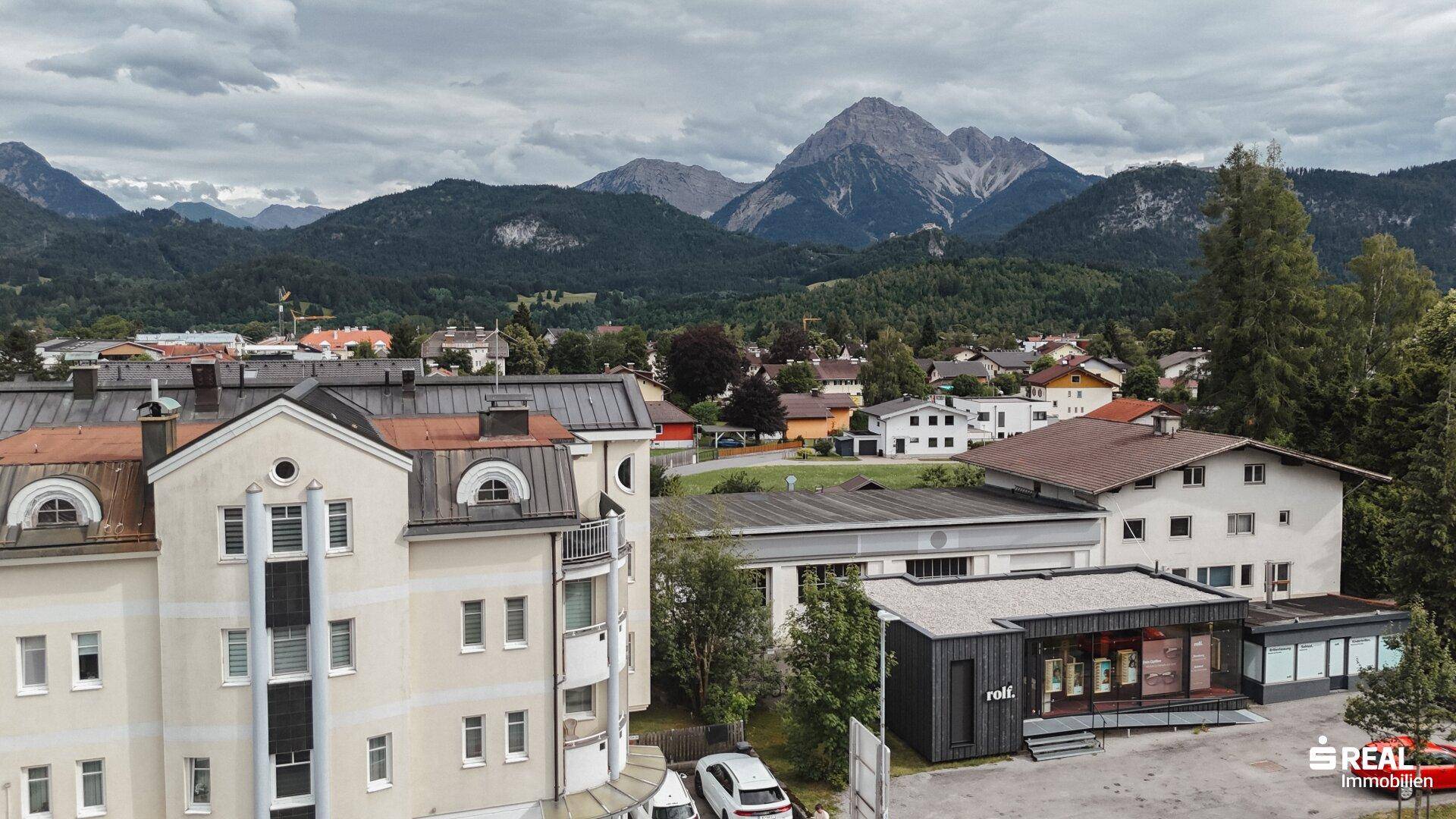 Blick über einen Teil der Stadt mit verschiedenen Gebäudetypen und einer weiten Bergkette im Hintergrund.