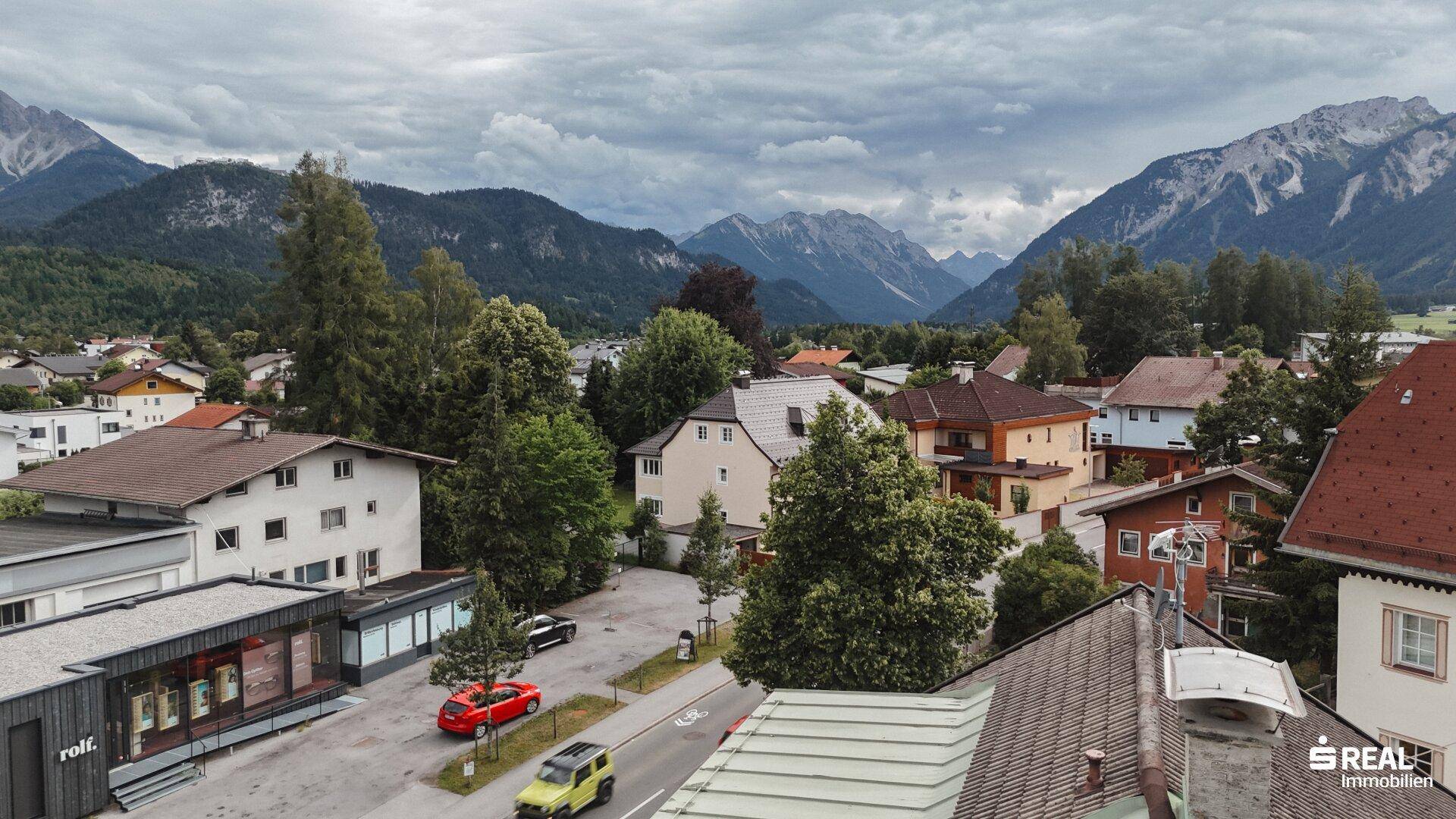 Weitblick über die Wohnbebauung und grüne Flächen der Stadt mit einer imposanten Bergkulisse.
