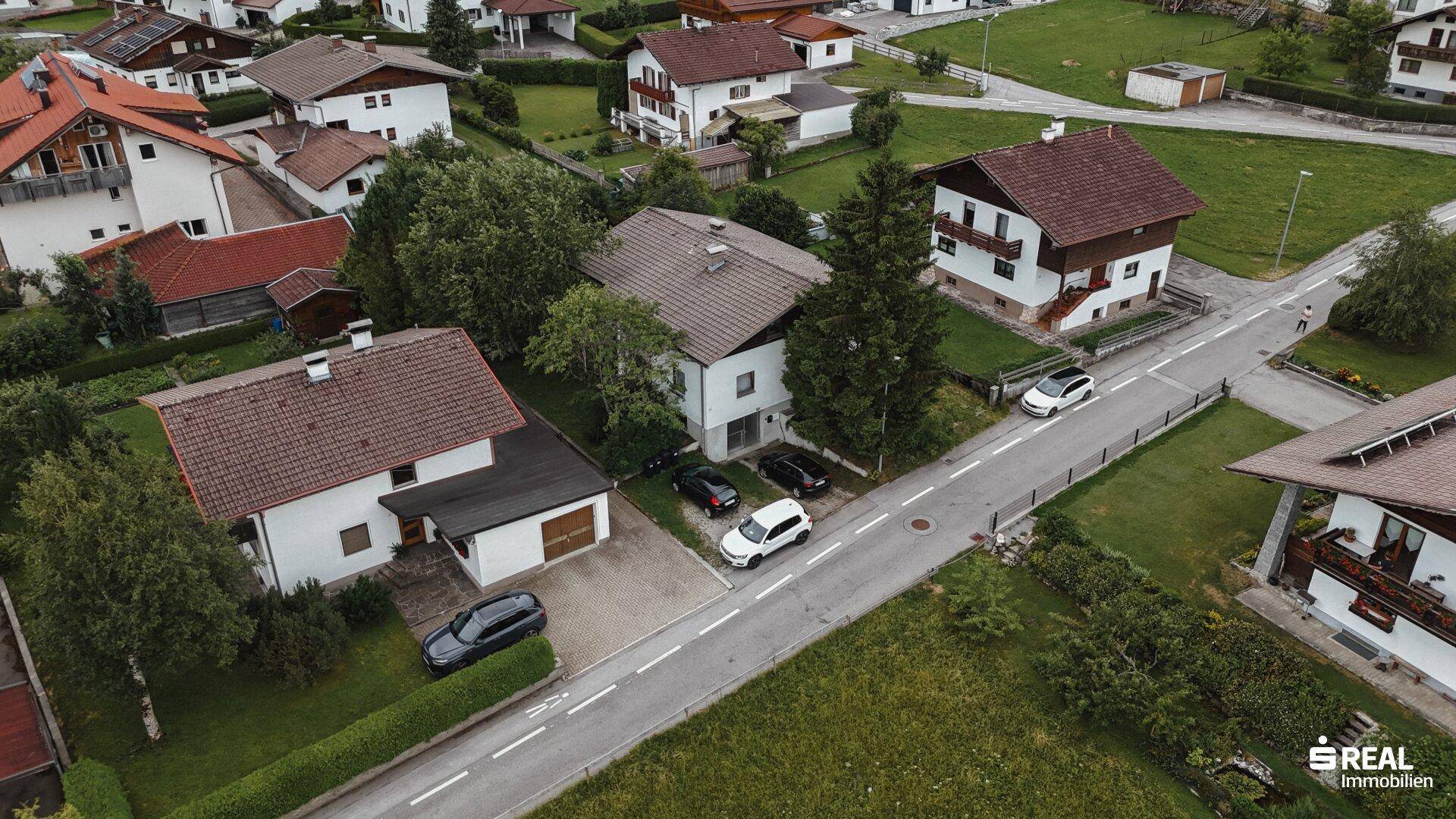 Luftaufnahme einer ruhigen Wohnstraße mit mehreren Einfamilienhäusern und gepflegten Gärten.