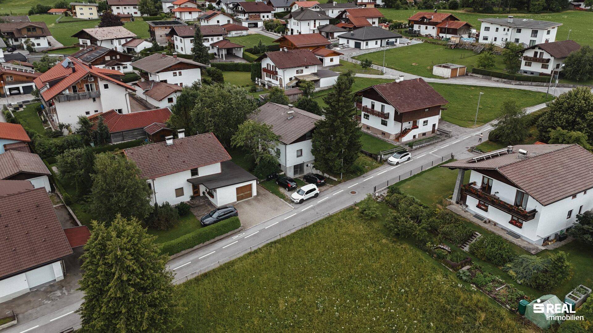 Weitläufige Luftaufnahme einer ländlichen Wohnsiedlung mit vielen Häusern und grünen Wiesen.