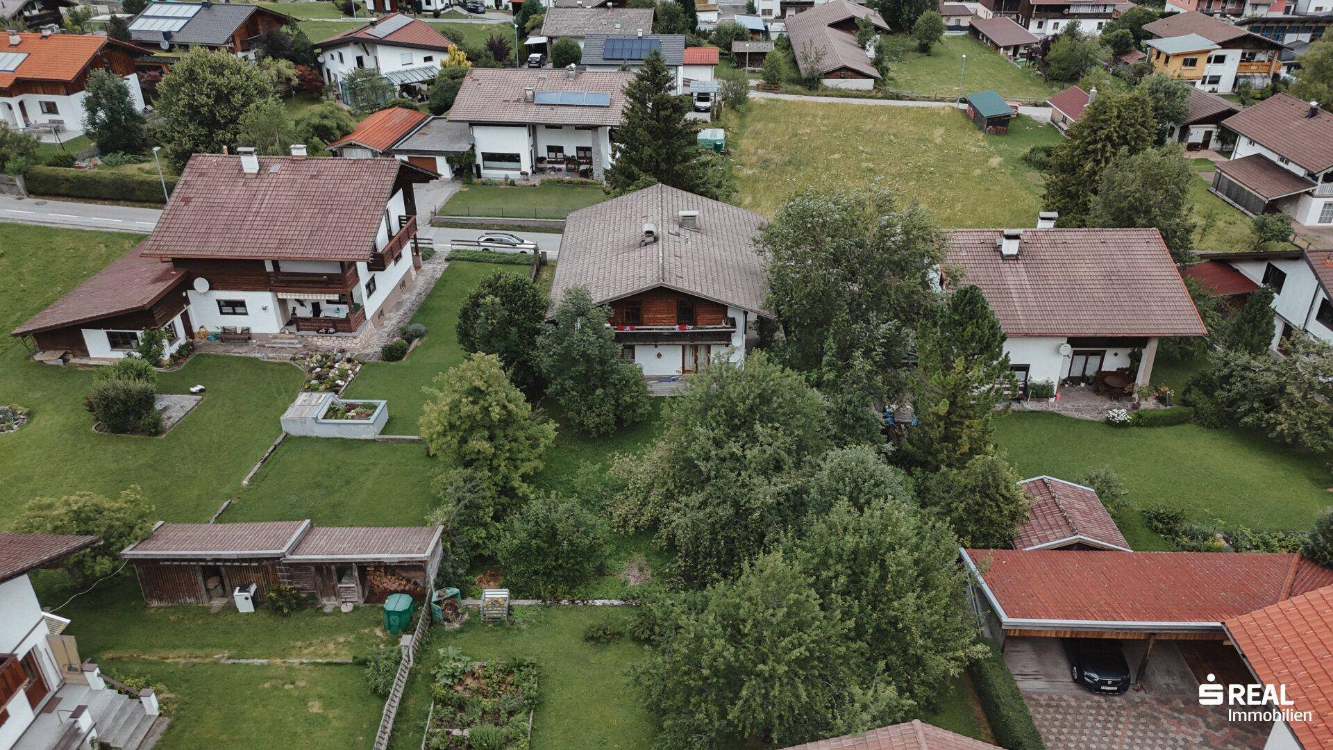 Weitwinkelaufnahme des Anwesens mit gepflegtem Garten und der angrenzenden Nachbarschaft.