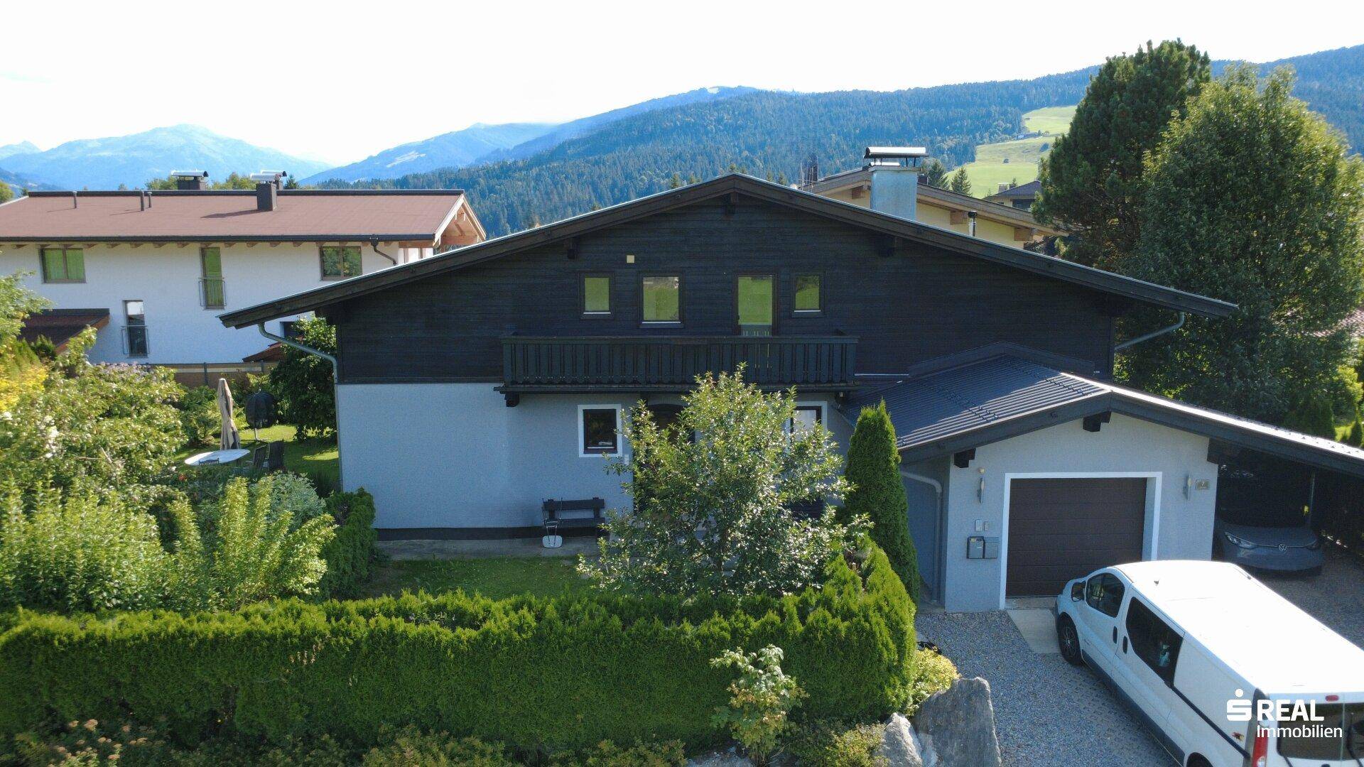 Vorderansicht des Hauses mit traditioneller Holzfassade, Carport und gepflegtem Vorgarten.