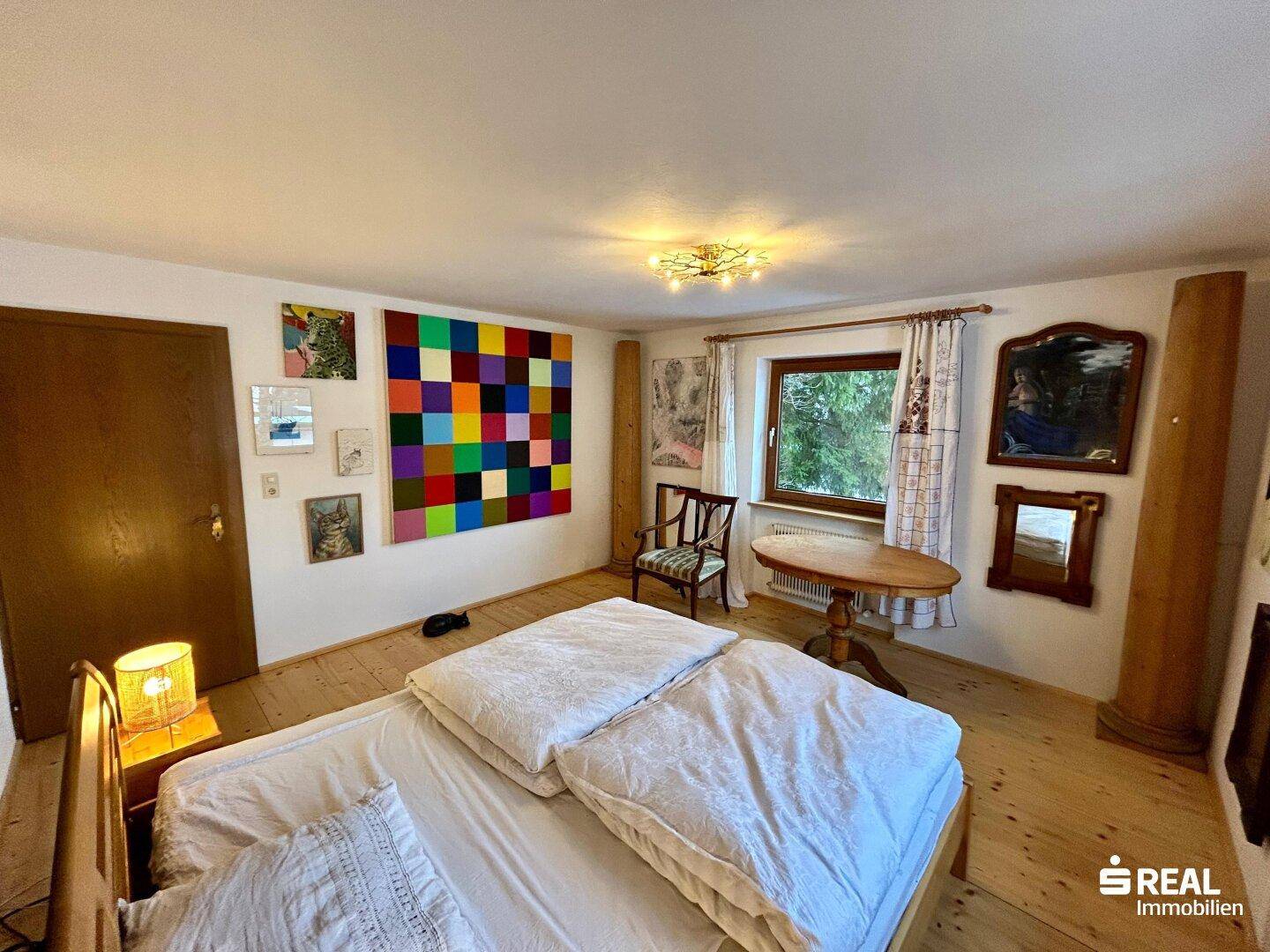 Schlafzimmer mit Holzbett, Holzboden und farbenfroher Wanddekoration.