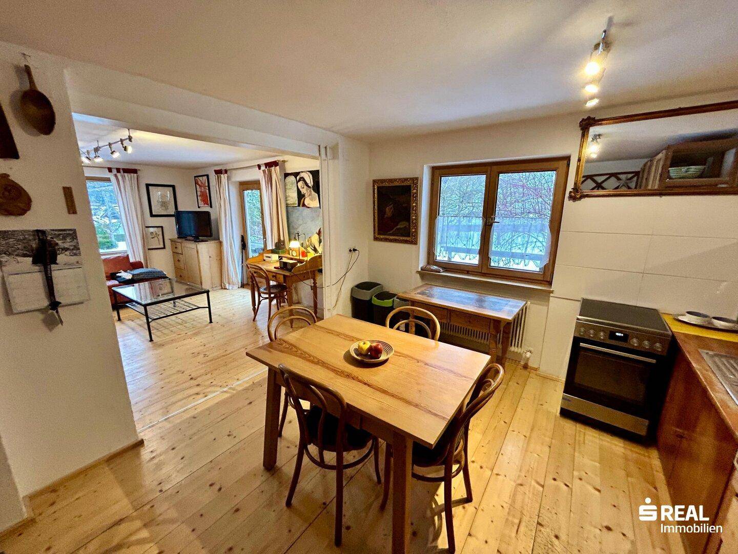 Essbereich mit Holztisch und Stühlen, offen zum Wohnzimmer, mit Holzboden.