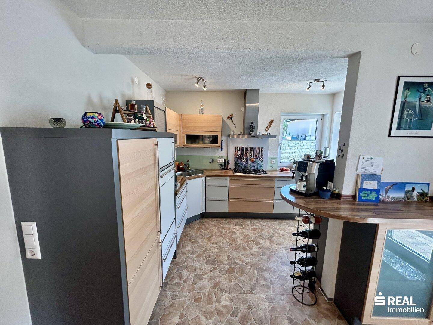 Funktionale Küche mit Holz- und Grautönen, integrierten Geräten und Frühstücksbar.