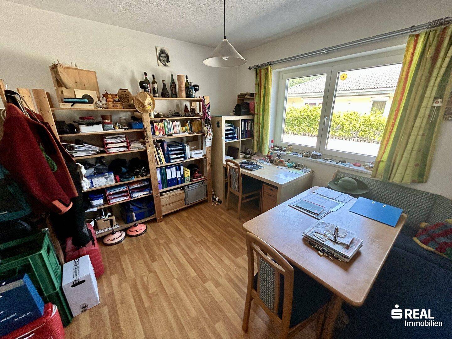 Funktionales Arbeitszimmer mit Schreibtisch, Regalen und großem Fenster für Tageslicht.