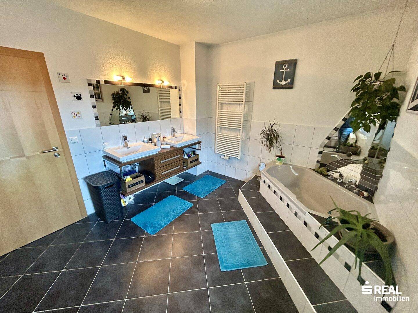 Modernes Badezimmer mit Doppelwaschbecken, Badewanne und beheiztem Handtuchhalter.