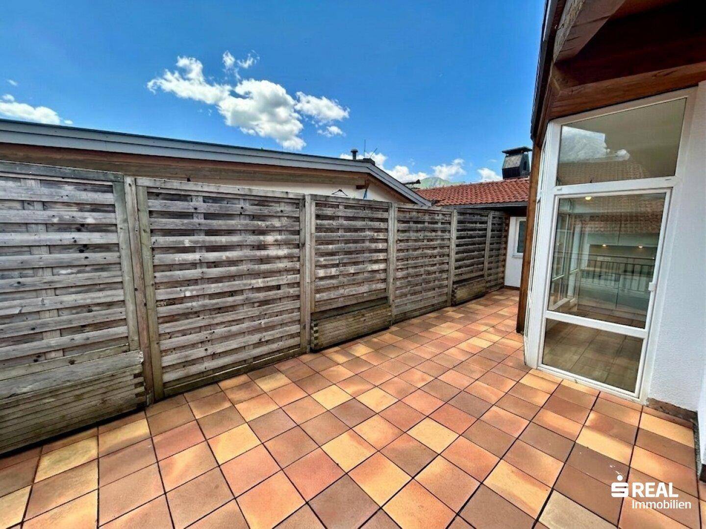 Lange Terrasse mit Holzzaun für Privatsphäre und Zugang zu weiteren Bereichen.