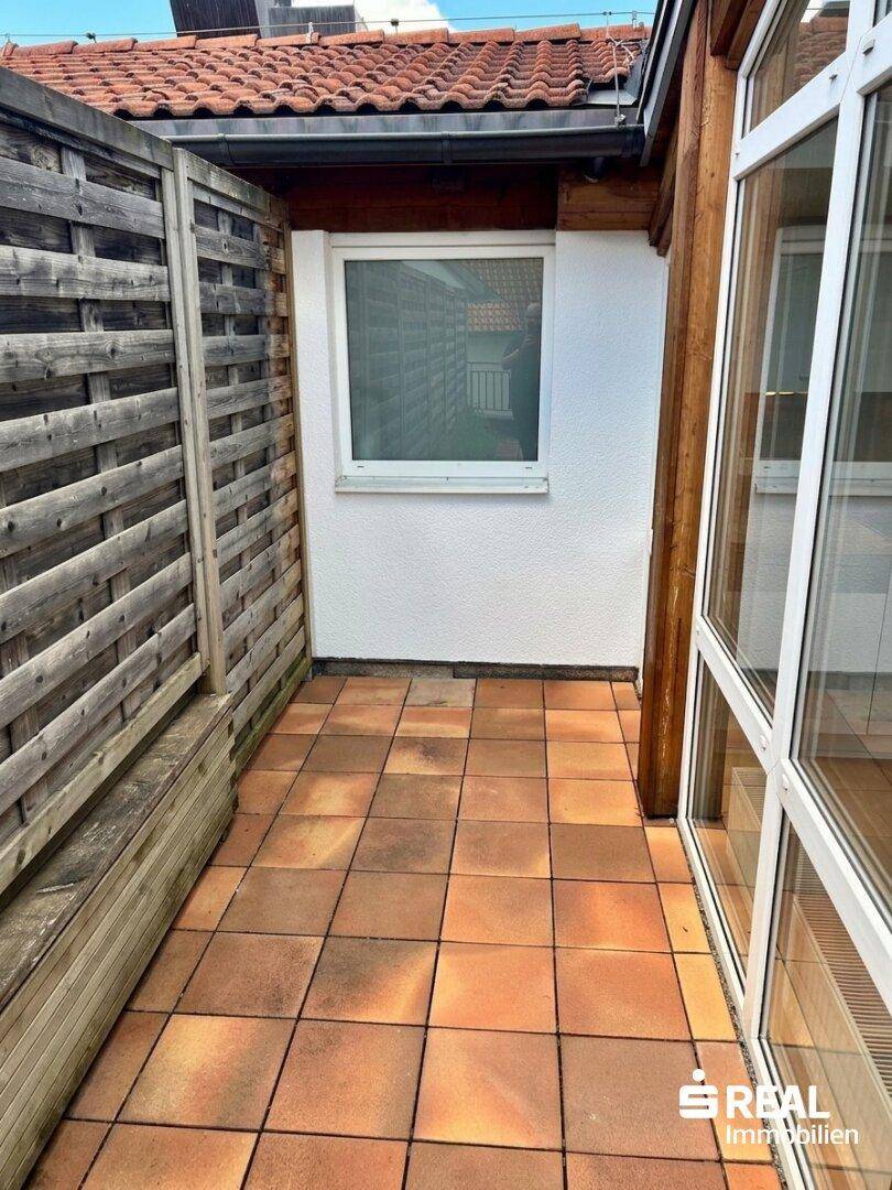 Schmalerer Bereich der Terrasse mit Fenster und Holzzaun für zusätzliche Privatsphäre.