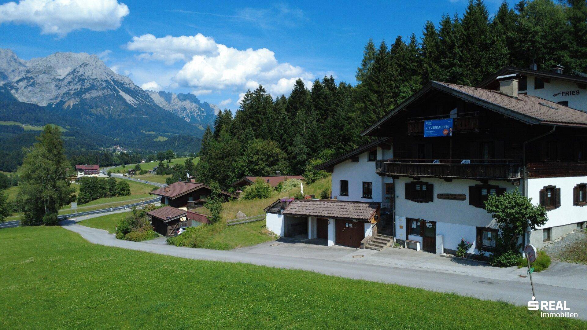 Weitläufige Ansicht des Anwesens mit Haupthaus und Garage, eingebettet in die malerische Berglandschaft.