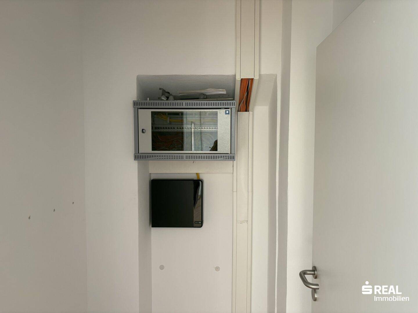 Wandmontierter Netzwerkschrank und Kabelmanagement in einem Technikraum, bereit für die IT-Infrastruktur.