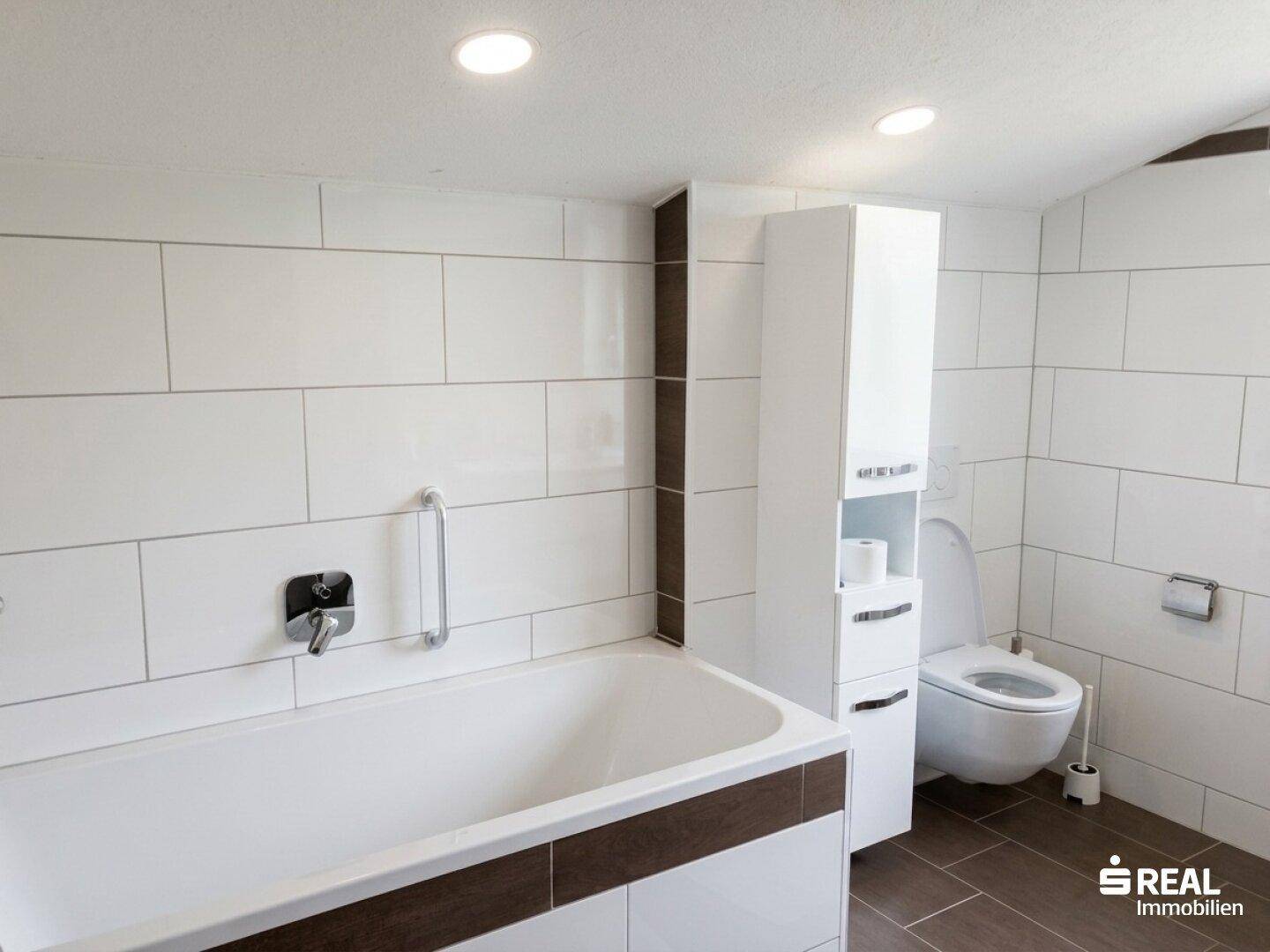Modernes Badezimmer mit Badewanne, weißen Fliesen und dunklen Akzenten.