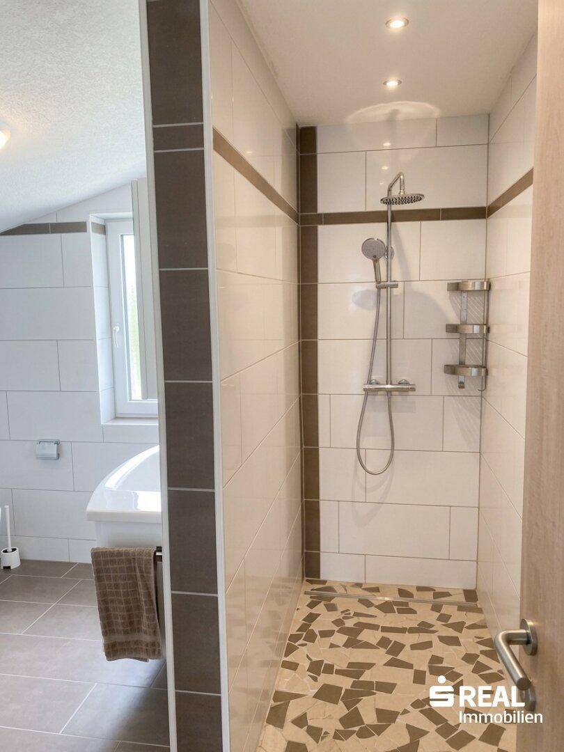 Modernes Badezimmer mit begehbarer Dusche, weißen Fliesen und Fenster.