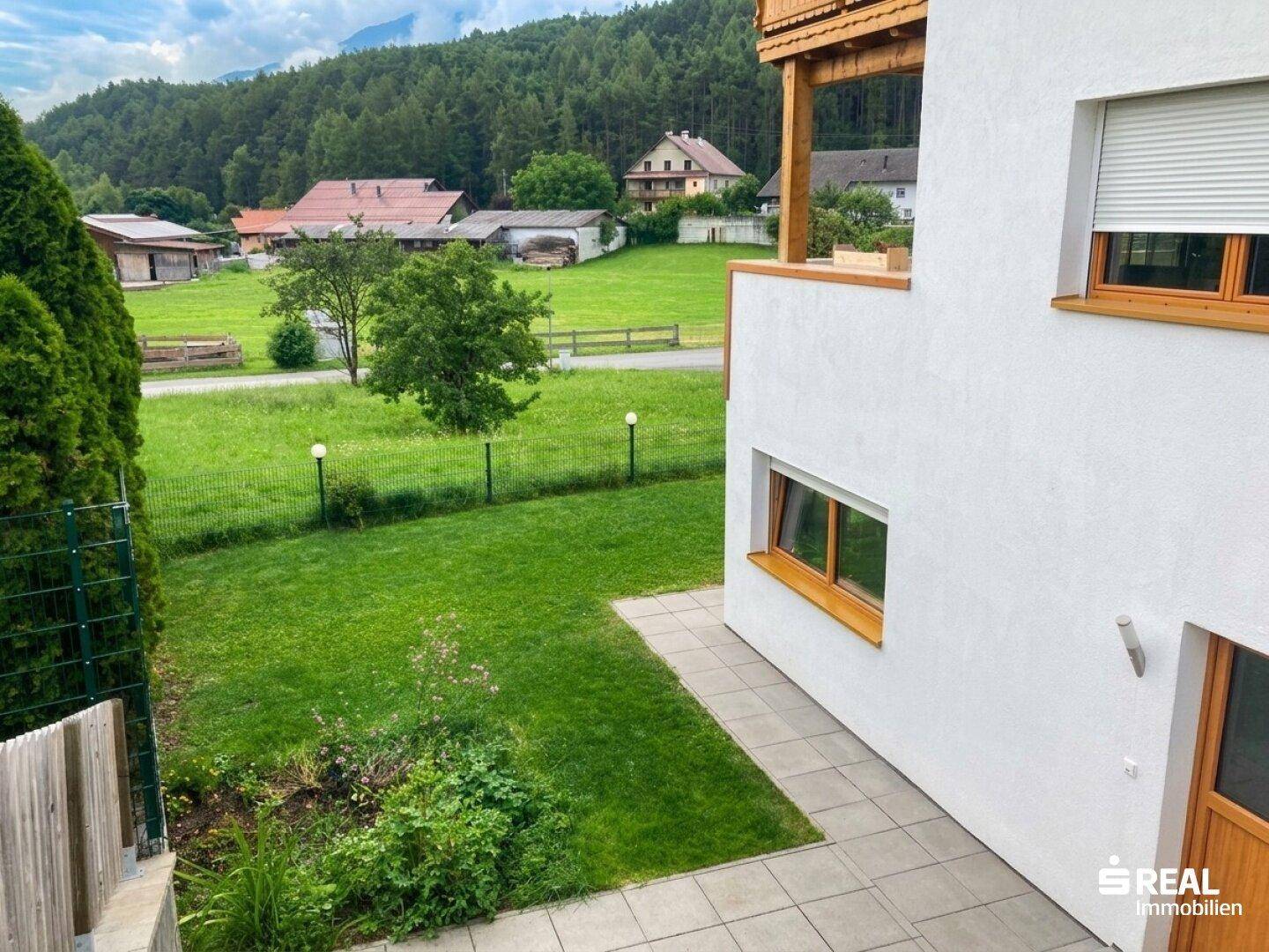 Kleiner gepflasterter Bereich neben einem grünen Rasen mit Blick auf die Landschaft.