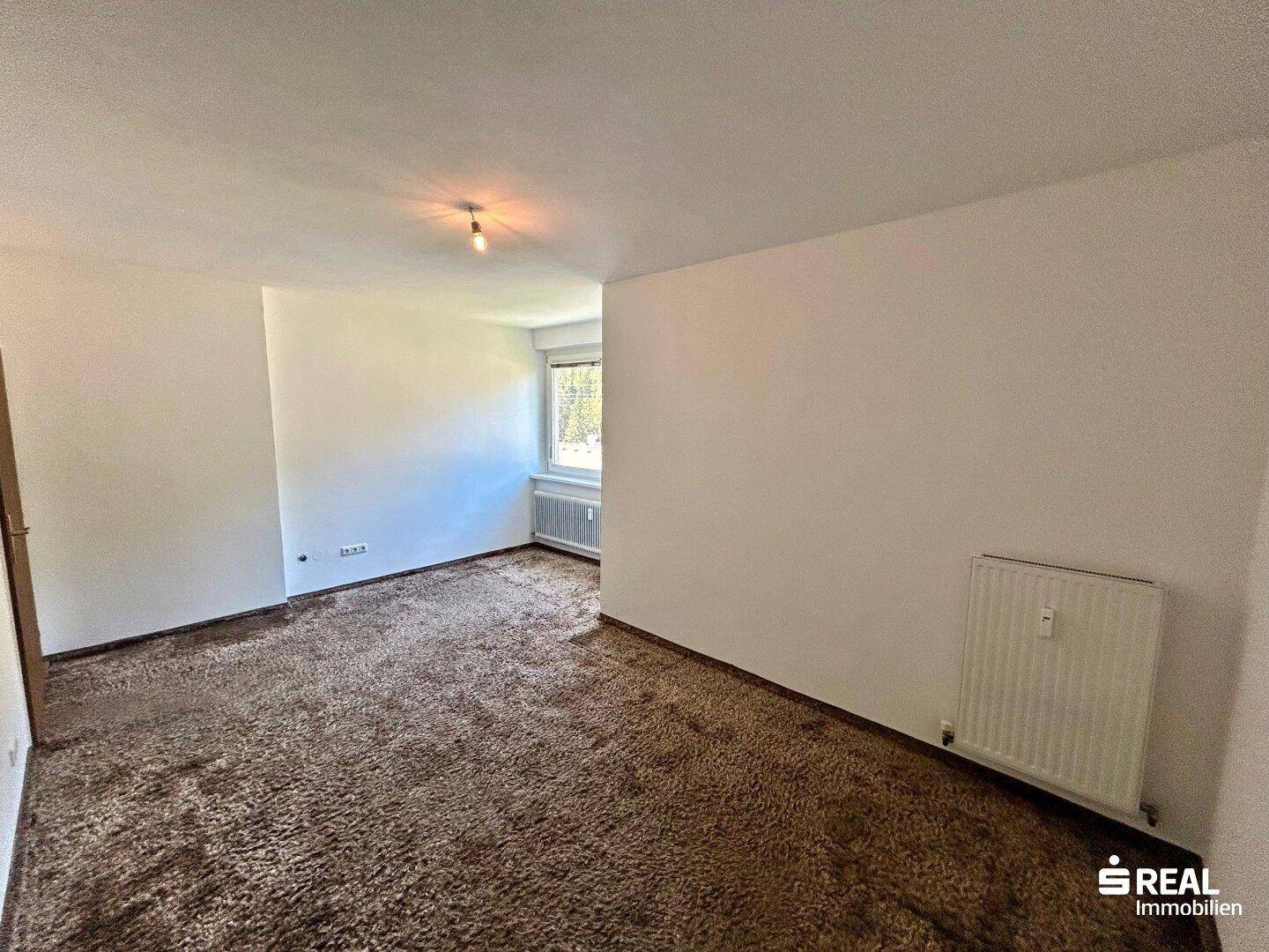 Schlafzimmer mit Teppichboden und Fenster, das viel Tageslicht hereinlässt und eine angenehme Atmosphäre schafft.