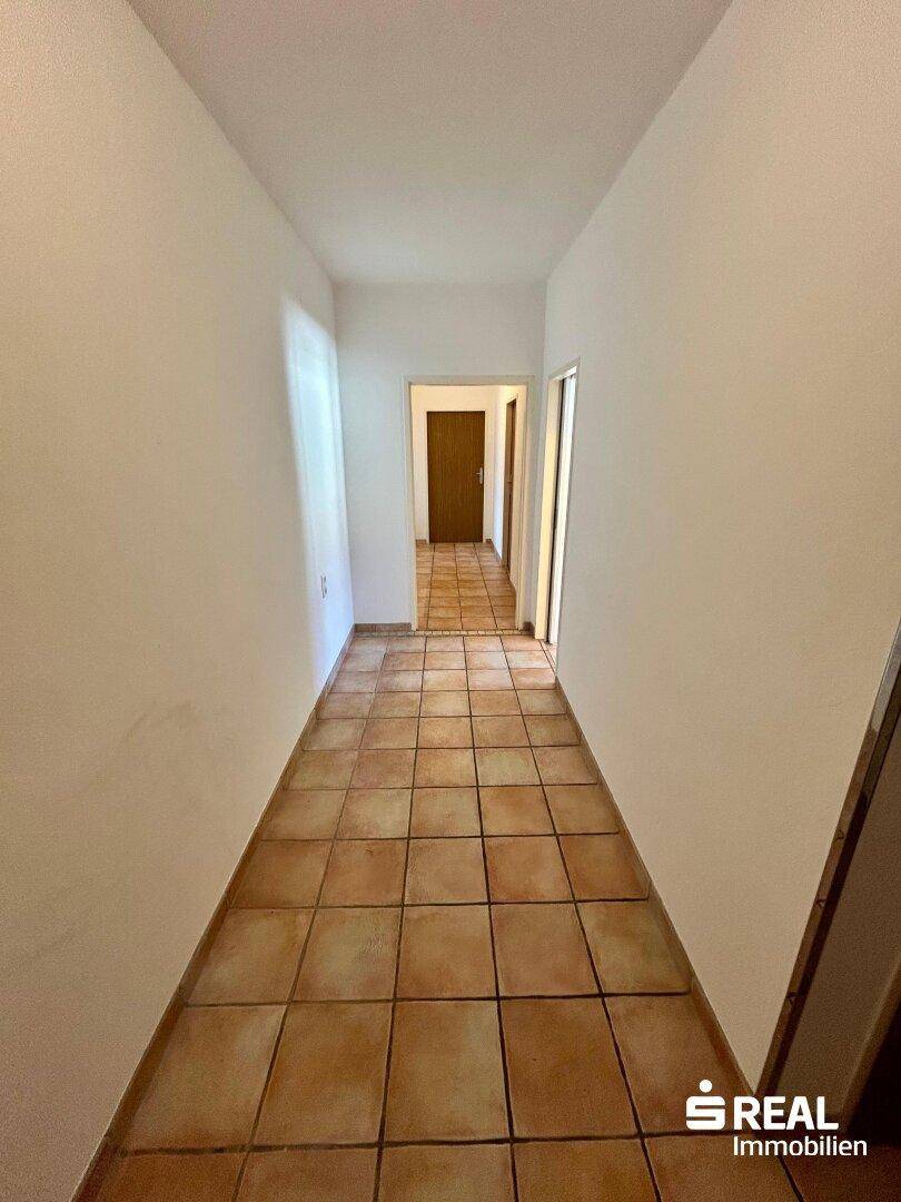 Langer Flur mit Terrakotta-Fliesenboden, der die verschiedenen Räume der Wohnung verbindet.