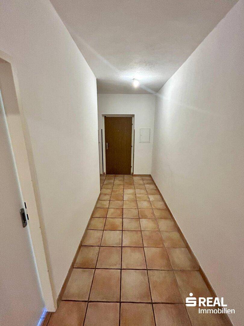Heller Eingangsbereich mit Terrakotta-Fliesenboden und Zugang zu den weiteren Zimmern.