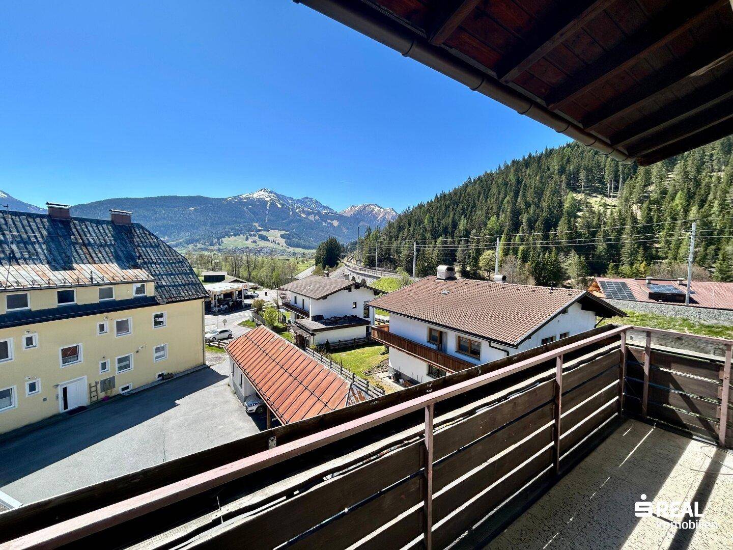 Sonniger Balkon mit Blick auf die grünen Hügel und die malerische Umgebung, ideal zum Entspannen.