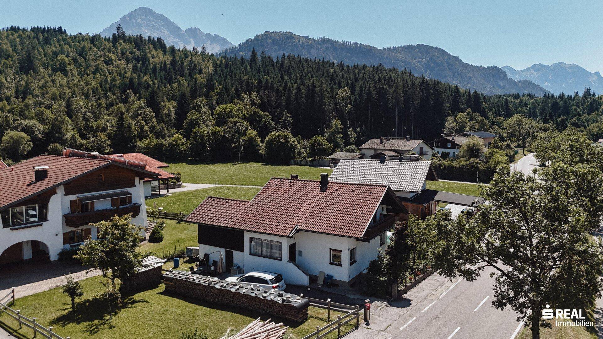 Ansicht des Hauses von der Straße aus mit Vorgarten und der malerischen Berglandschaft im Hintergrund.