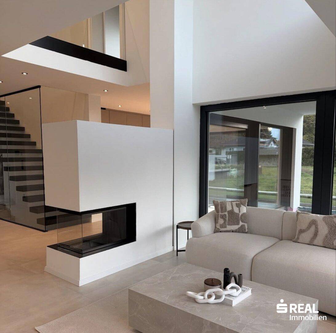 Geräumiges Wohnzimmer mit modernem Kamin, bequemer Couch und Blick auf eine elegante Treppe.