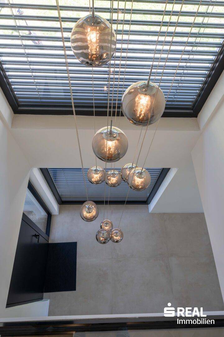 Moderner Treppenaufgang mit hängenden Kugelleuchten und Oberlicht, das viel Licht hereinlässt.