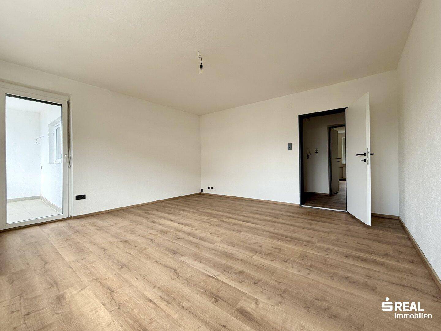 Geräumiges, unmöbliertes Zimmer mit Laminatboden und Zugang zu einem Außenbereich.