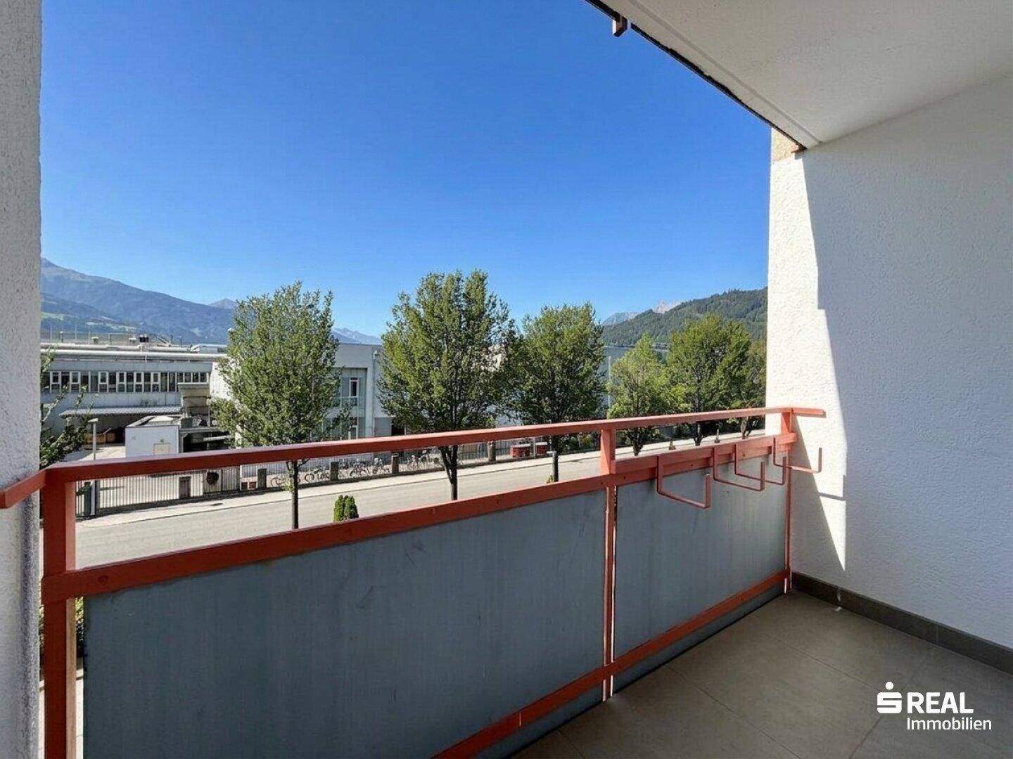 Balkon mit orangefarbenem Geländer bietet einen weiten Blick auf die Berge und die Umgebung.
