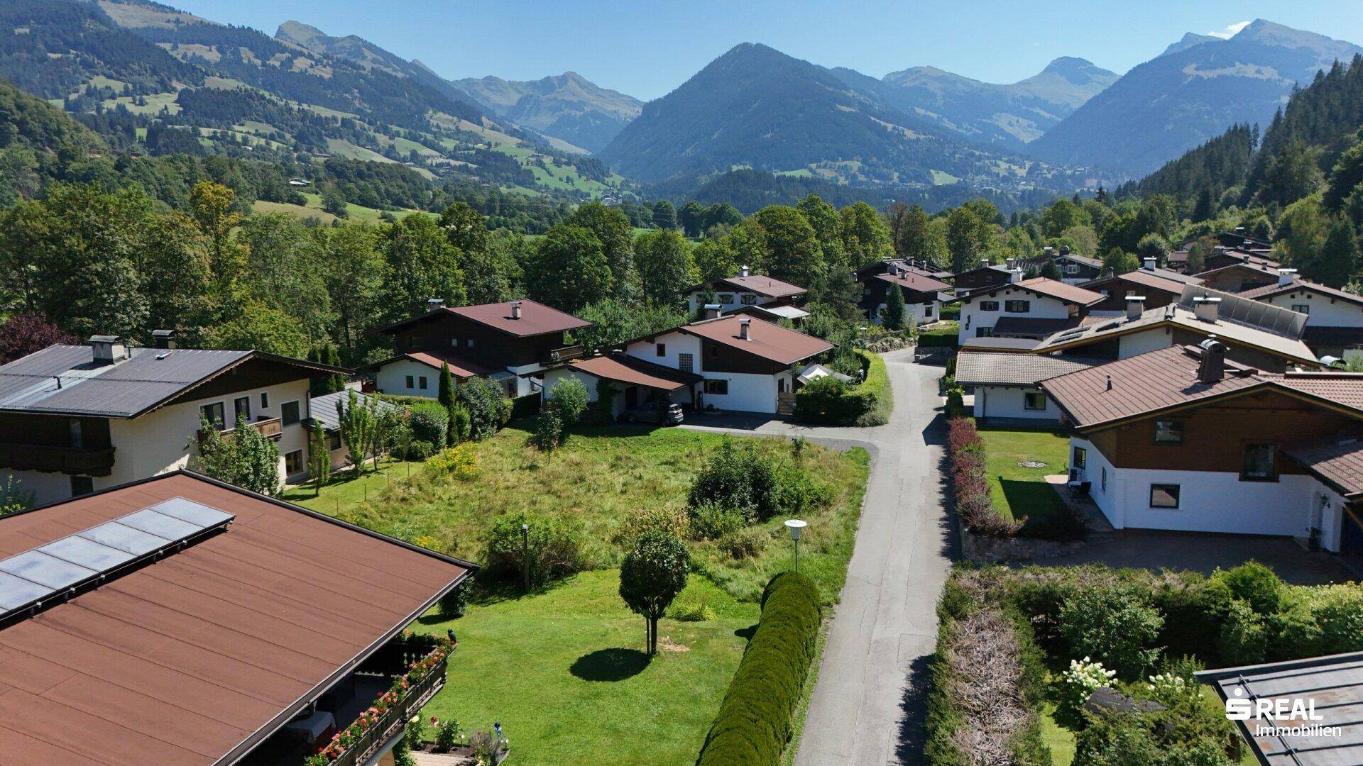 Nahaufnahme aus der Luft einer Wohngegend mit Einfamilienhäusern, gepflegten Gärten und Bergblick.