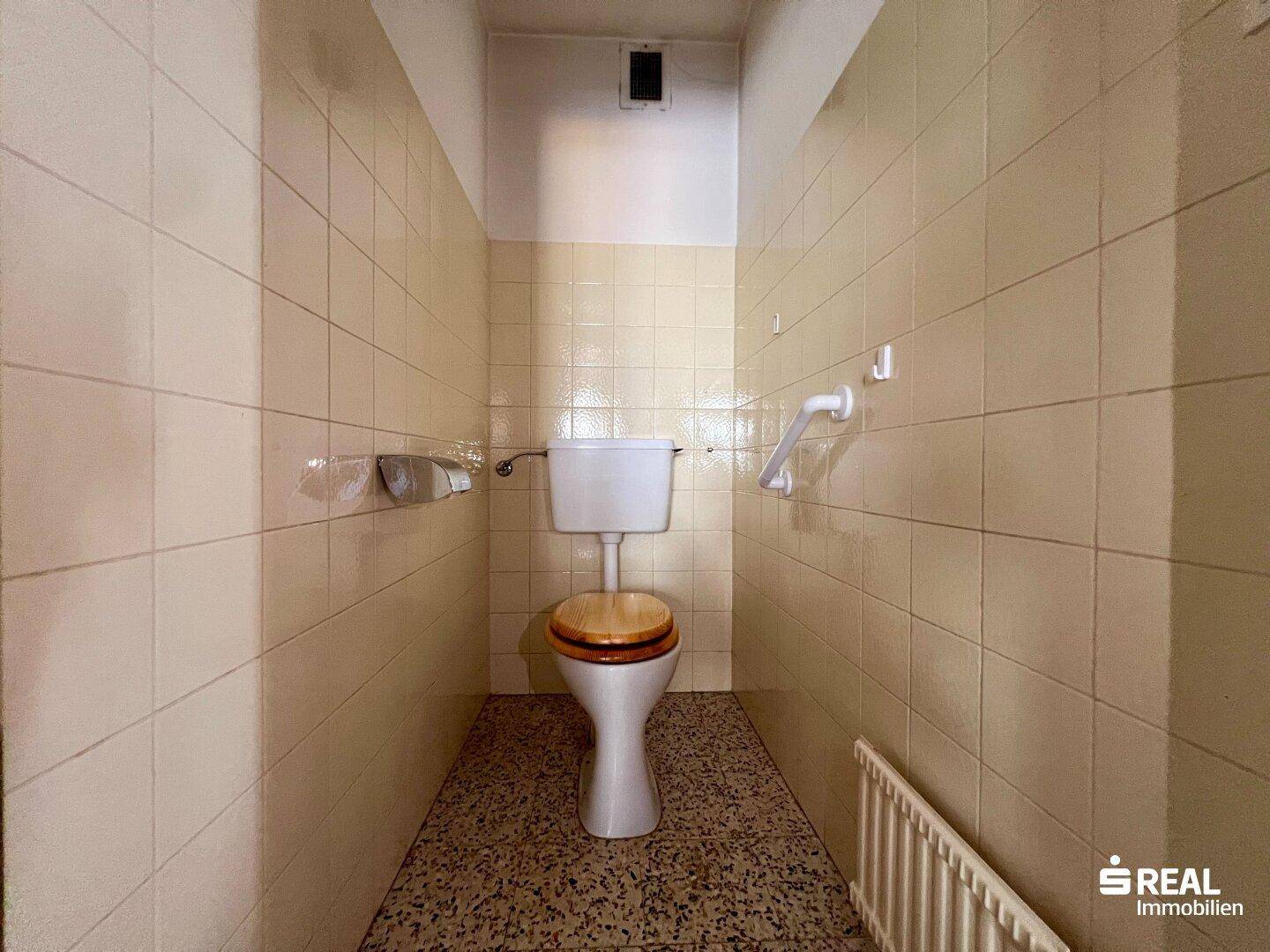 Separate Toilette mit beigen Fliesen und WC.