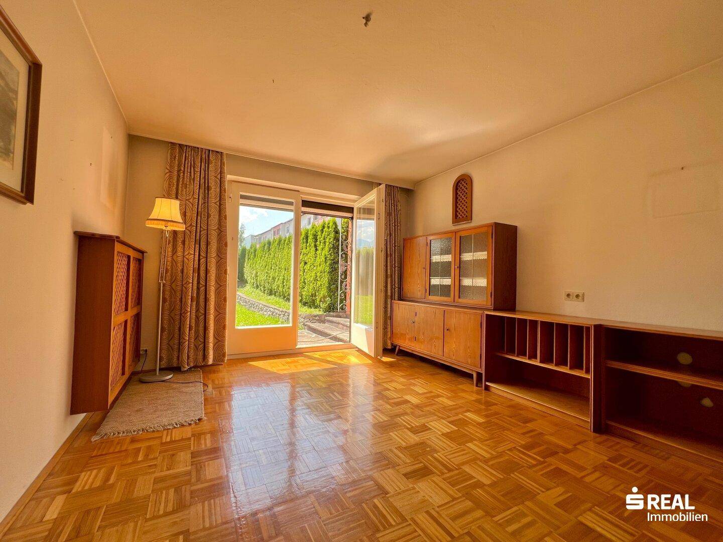 Geräumiges Wohnzimmer mit Parkettboden und Zugang zum Garten.