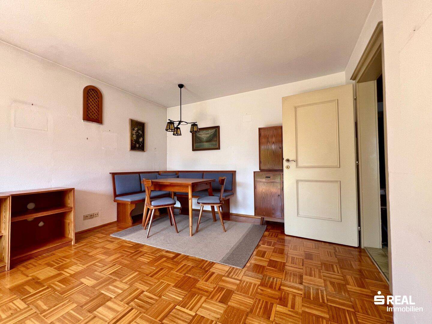 Essbereich mit Holzboden, traditionellen Möbeln und einem Teppich.