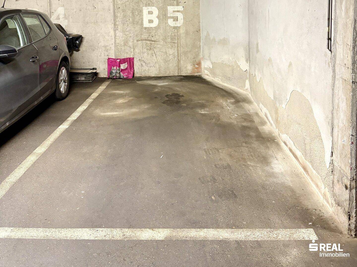 Tiefgaragenstellplatz mit Betonwänden und -boden, bietet sicheren Parkraum für ein Fahrzeug.