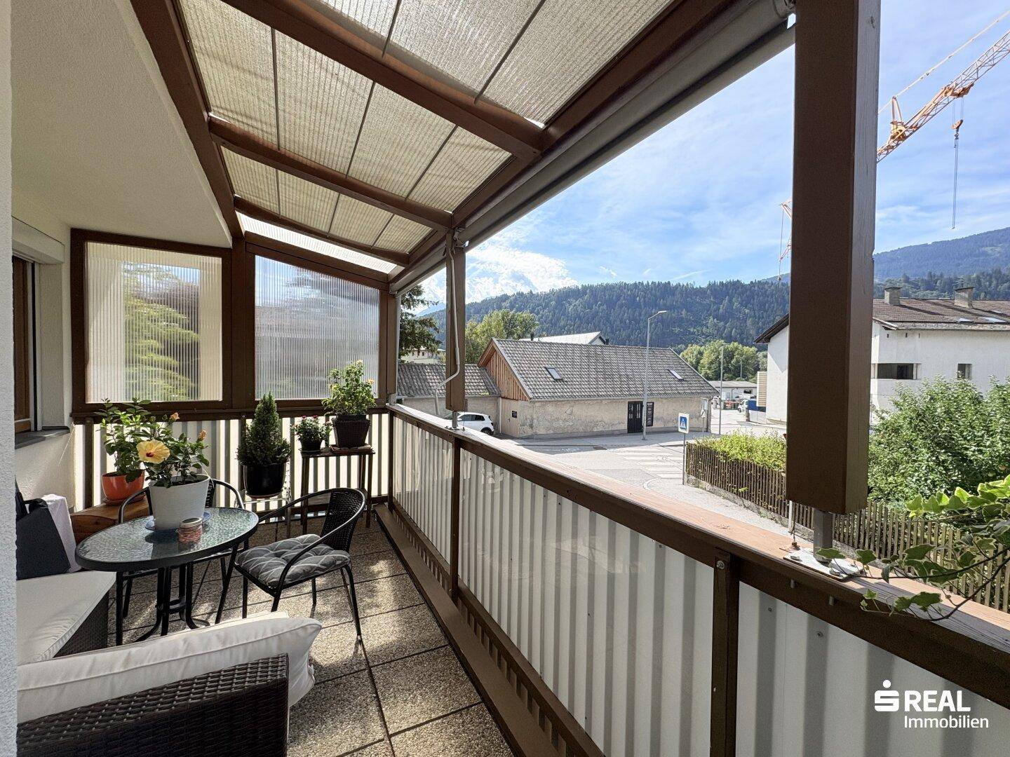 Überdachter Balkon mit Sitzgelegenheiten und Bergblick, ideal zum Entspannen im Freien.