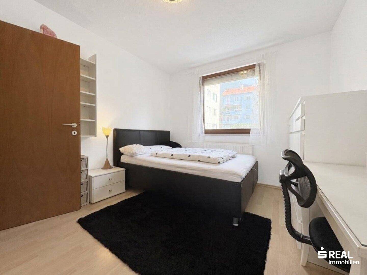 Helles Schlafzimmer mit Einzelbett, Schreibtisch und Regal, ideal als Kinder- oder Gästezimmer.