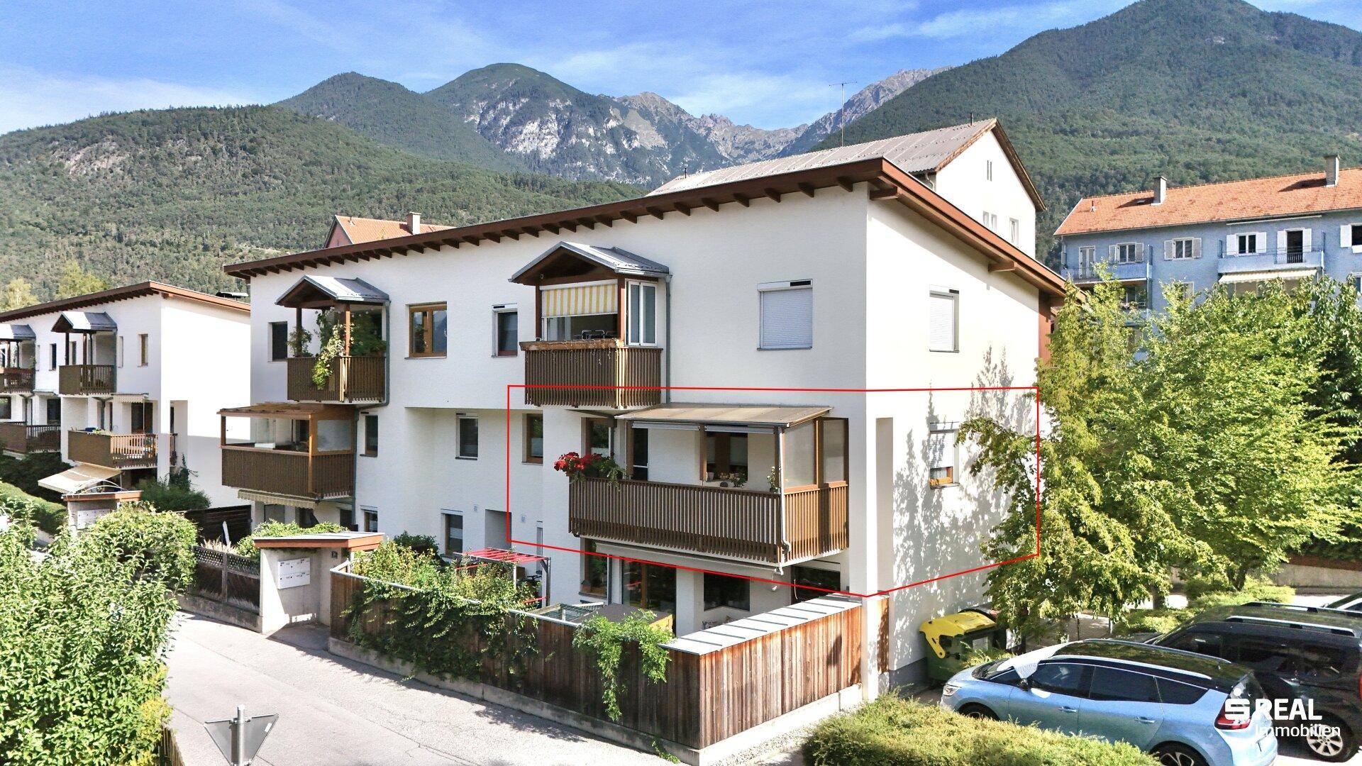 Mehrfamilienhaus mit mehreren Balkonen und Blick auf die umliegende Berglandschaft.