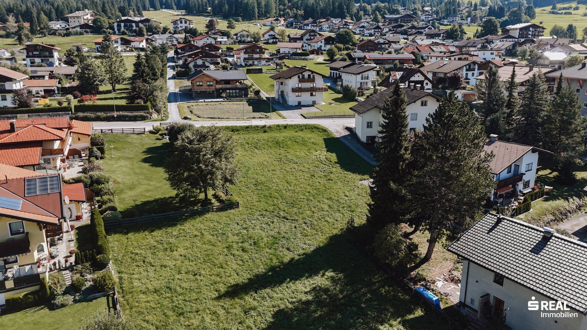 Weitläufiges grünes Grundstück mit Blick auf ein Dorf und die umliegende Landschaft.