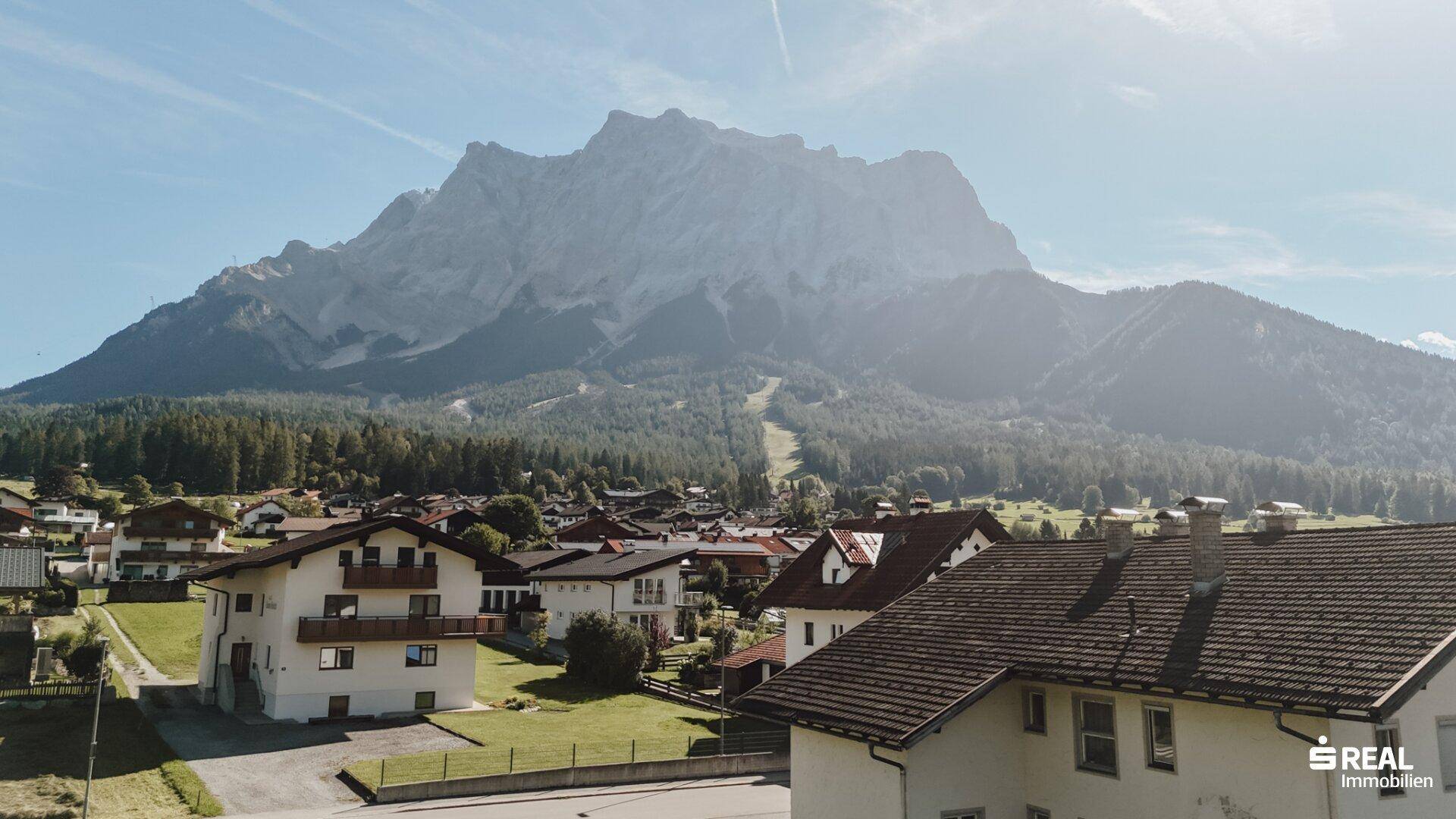 Panoramablick auf ein Dorf mit traditionellen Häusern und einem majestätischen Berg im Hintergrund.