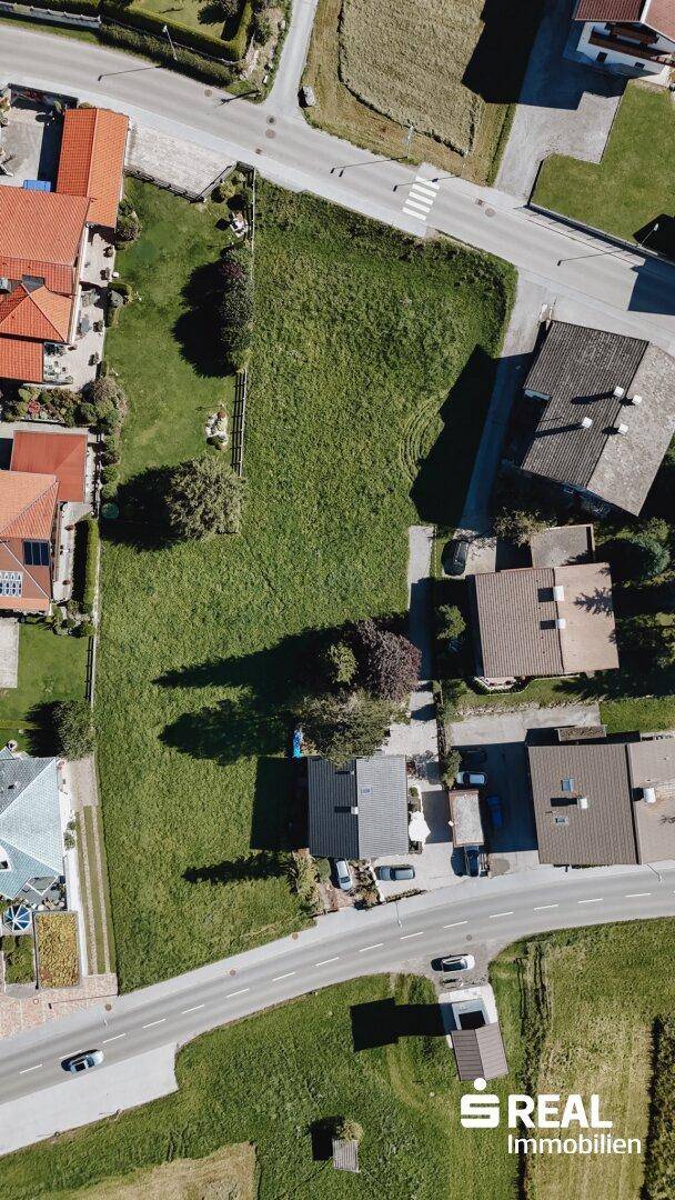 Vertikale Luftaufnahme eines weitläufigen grünen Grundstücks, umgeben von Wohngebäuden und Straßen.