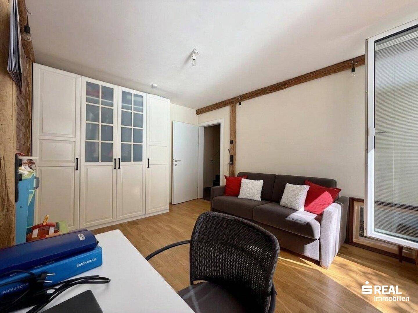 Helles Zimmer mit Holzboden, Einbauschränken und einem Schreibtisch, ideal als Büro oder Gästezimmer.