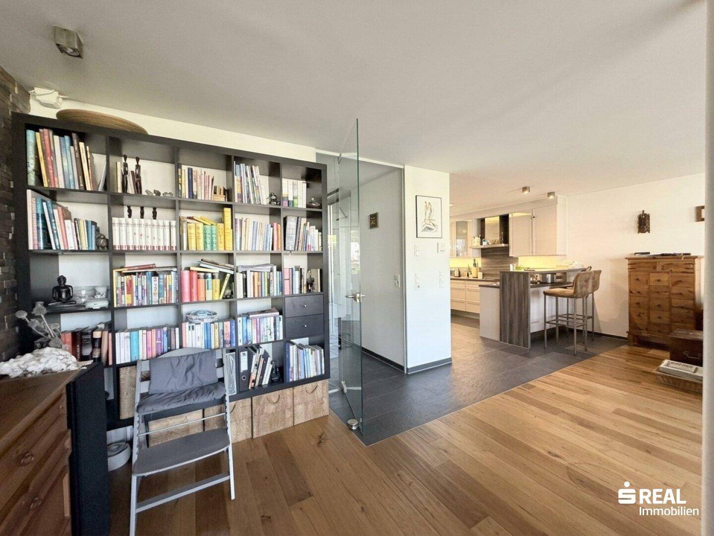 Übergangsbereich zwischen Wohnzimmer und moderner Küche mit Bücherregal und Bartheke.