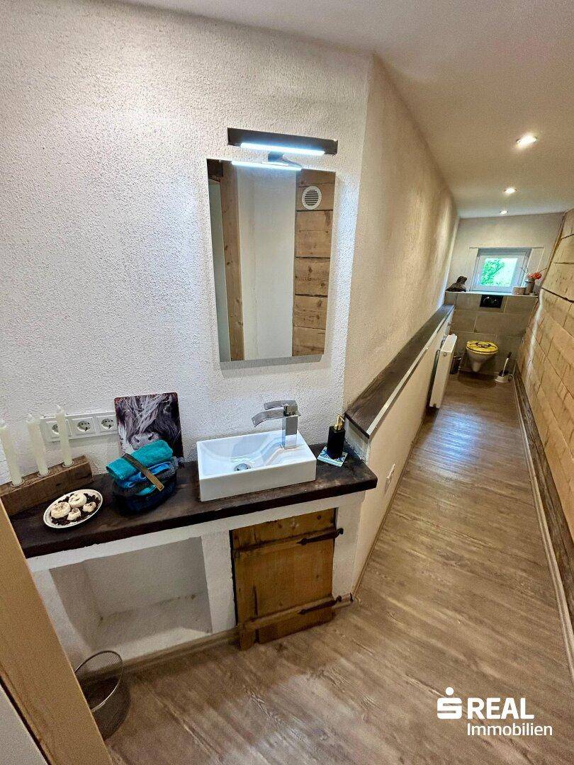 Kleiner Waschbereich im Flur mit modernem Waschbecken und Zugang zur Gästetoilette.