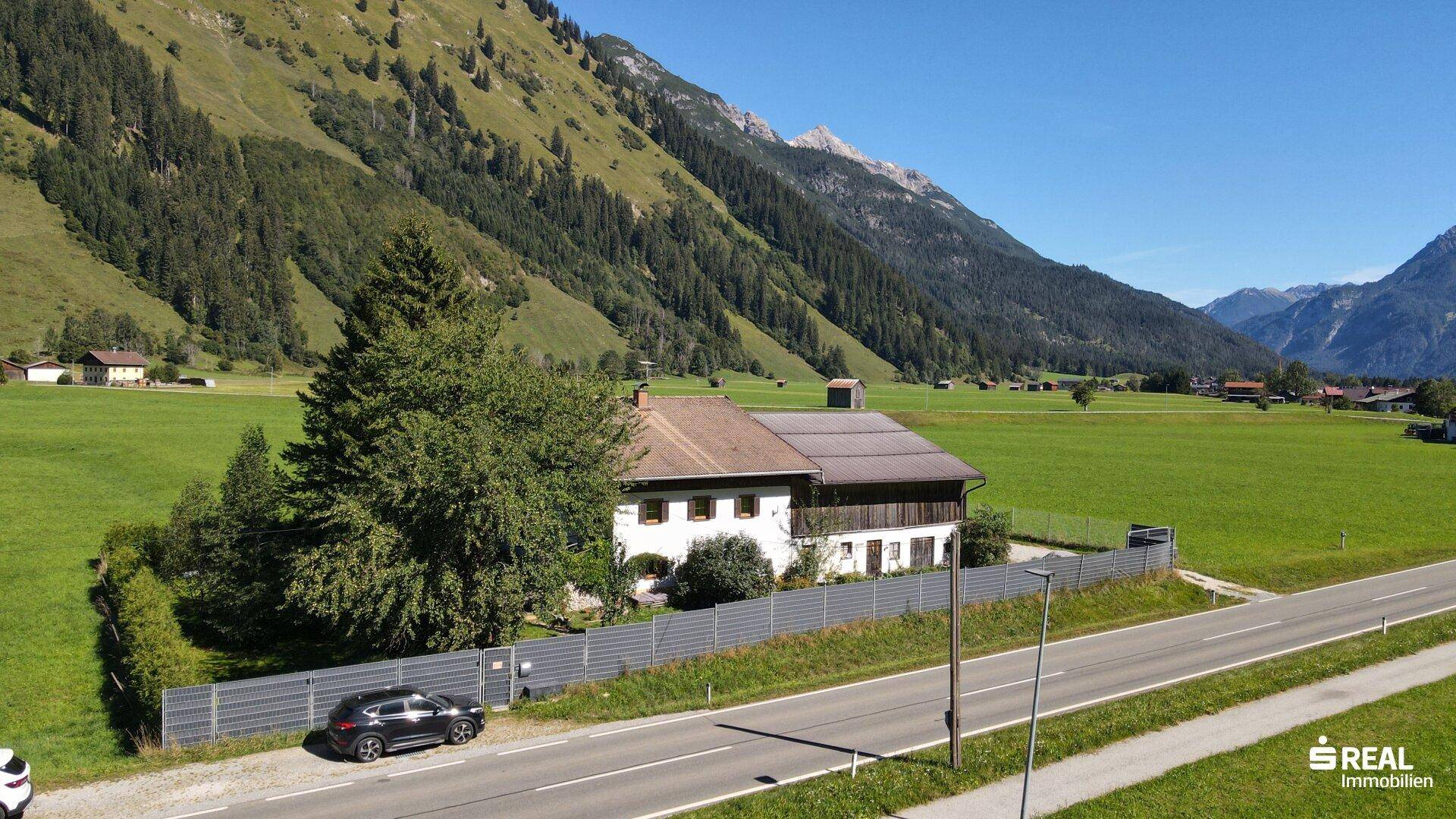Ansicht des Hauses in alpiner Landschaft mit grünen Wiesen und majestätischen Bergen im Hintergrund.