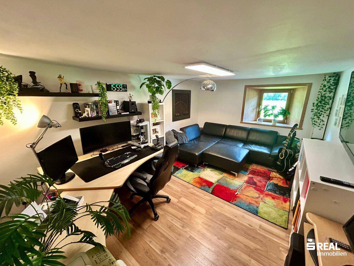 Modern eingerichtetes Büro mit großem Schreibtisch, bequemer Couch und farbenfrohem Teppich.