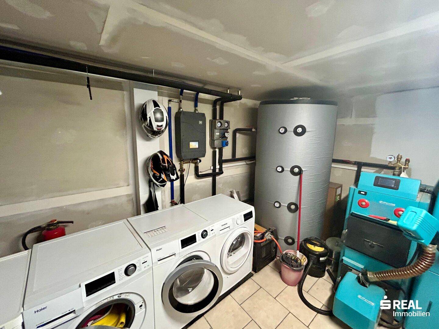 Praktischer Hauswirtschaftsraum mit Waschmaschinen, Warmwasserspeicher und Heizungsanlage.