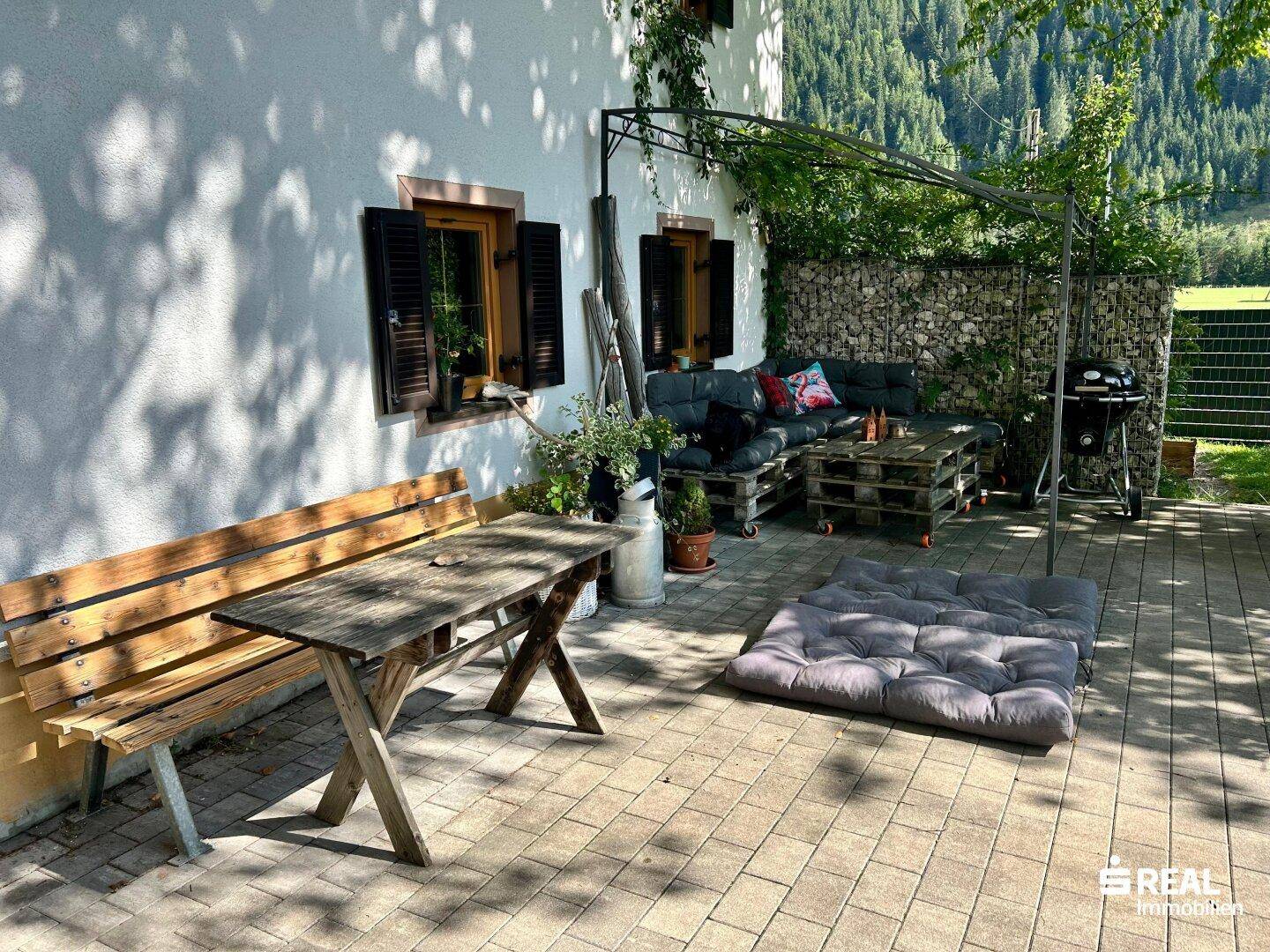 Gemütliche Terrasse mit Palettenmöbeln, Grillplatz und Blick auf die umliegenden Berge.
