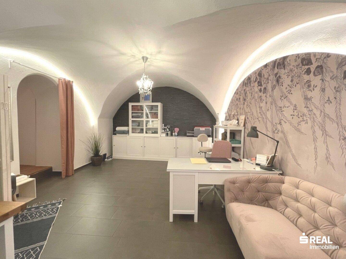 Helles Büro mit Gewölbedecke, moderner Einrichtung und dekorativer Wandgestaltung in einem Altbau.
