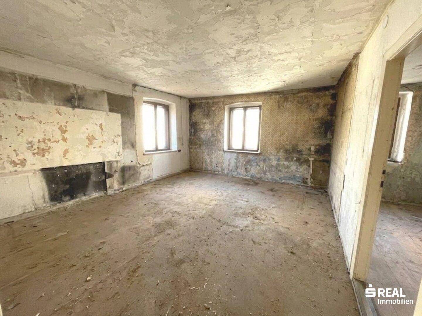 Renovierungsbedürftiger Raum mit alten Fenstern und abgenutzten Wänden, bereit für Umgestaltung.